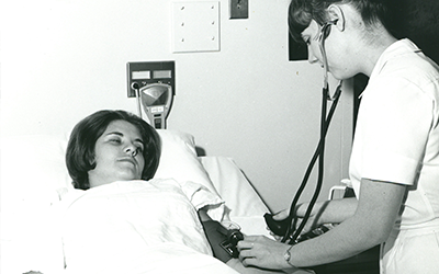 1971 Nursing student taking another students blood pressure.