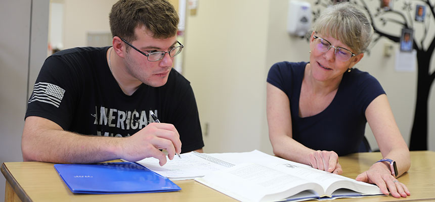 A student and his tutor looking at the textbook.