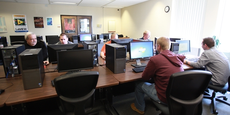 Several men work at computers in the computer lab