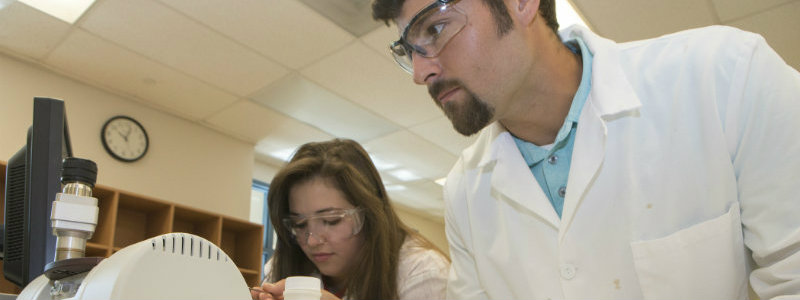 2 students working together on a lab project in white coats.