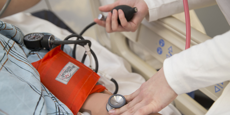 A student taking a patients blood pressure.
