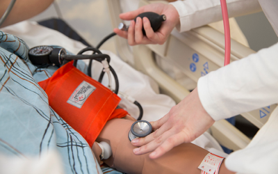 Nurse's hands and blood pressure cuff around patient's arm