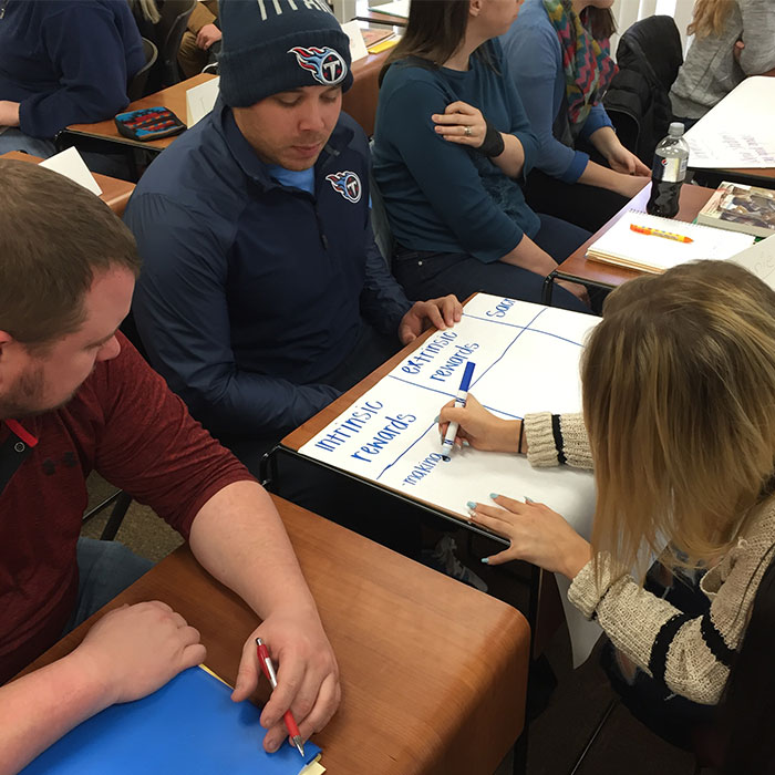 Group of students working at a table and writing on a large piece of paper
