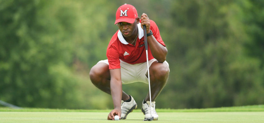 Men's golf player squatting on the green reading his putt