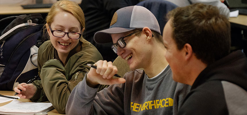 Three students sitting at a table laughing.