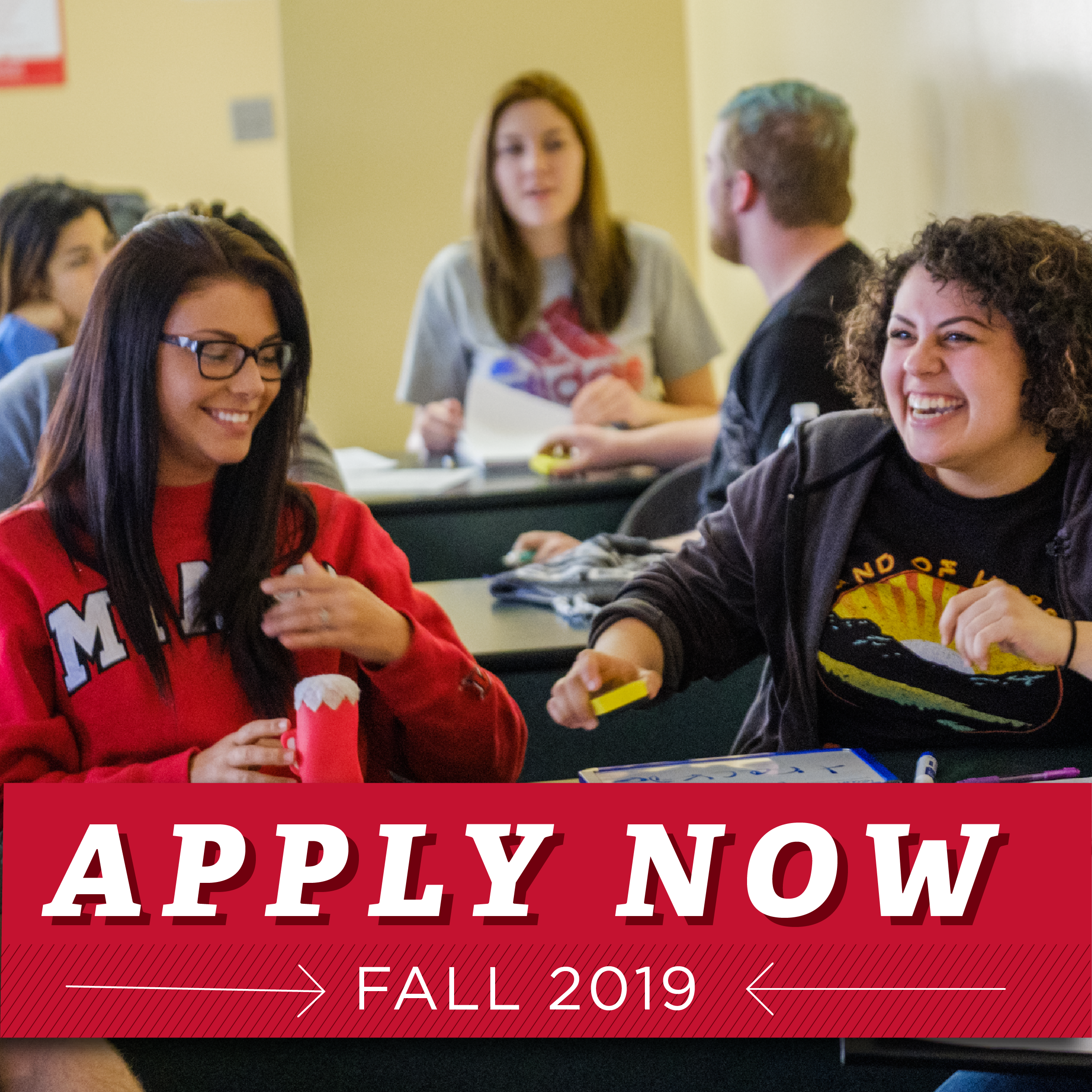 Apply Now for Fall 2019. Students sitting at their desks in a circle laughing.