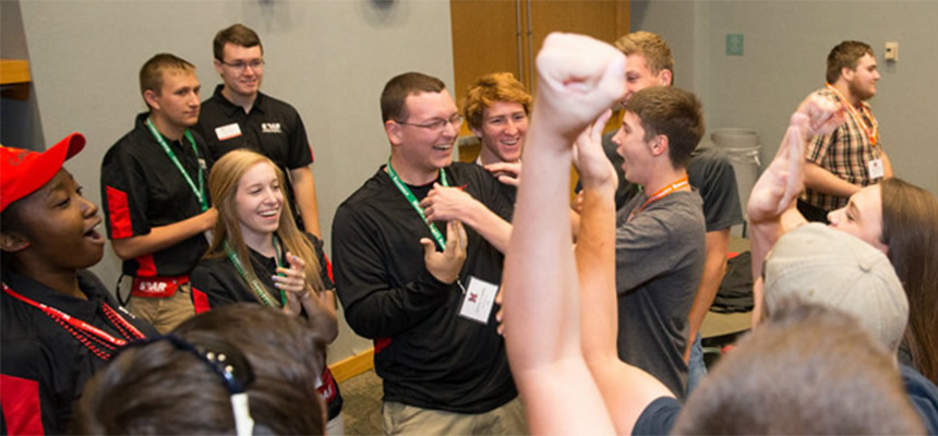Students smiling in a circle during an icebreaker event.