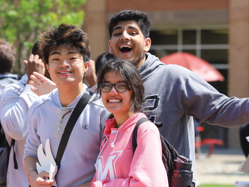 3 students smiling, having fun at Spring Fling in the Hamilton Campus Quad