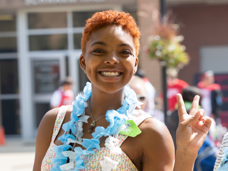 A student smiling while holding up the peace sign.