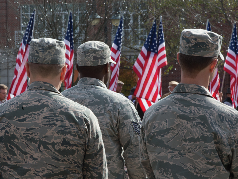 Military members standing in a row facing the flag.