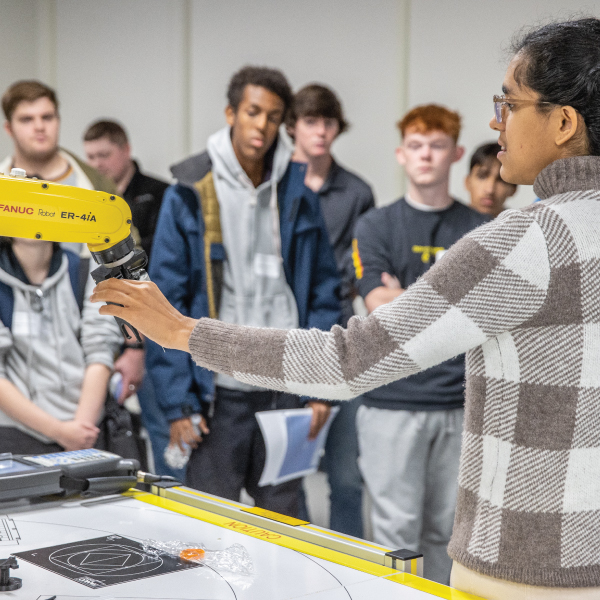 A professor showing students a robot in the robotics lab on the Middletown campus.