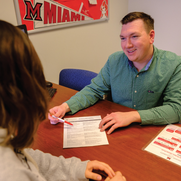 A student meeting with an academic advisor to talk about scheduling classes.