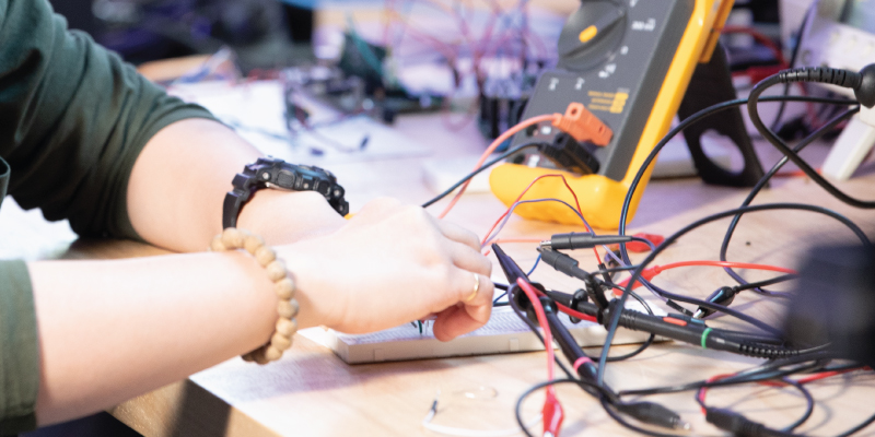 A students hands working on an electrical project.
