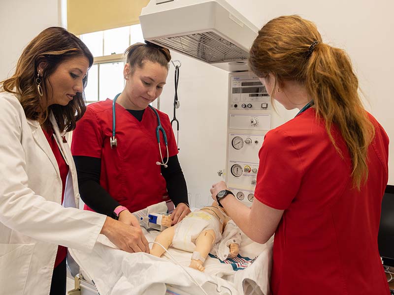 Nursing students are working in the lab with the SIM baby.