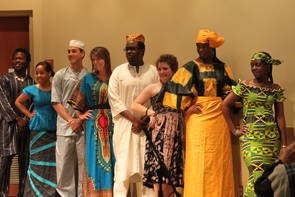 About 8 people of various ethnicities dressed in African clothes, posing in a line for the camera