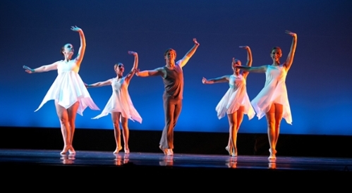Five dancers twirling on a stage