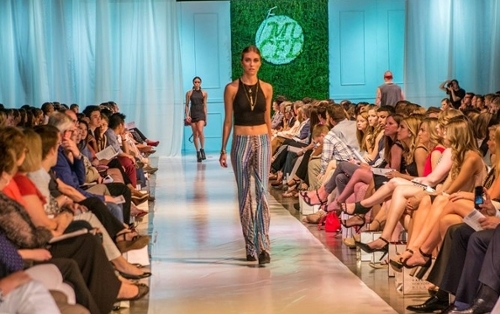Model student walking down a fashion runway with crowd surrounding her.