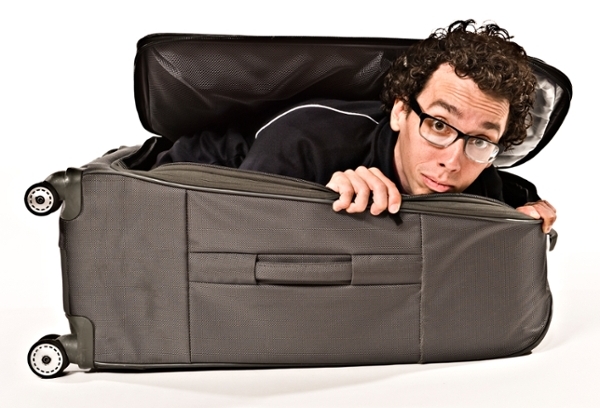 Jonathon Burns with head and shoulders peeking out of a large suitcase