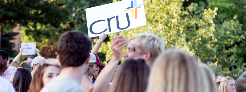 A student at Mega Fair holds up a sign advertising the Christian student group Cru