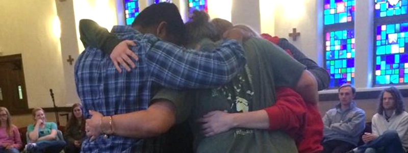 Students in a group hug during a Christian worship service