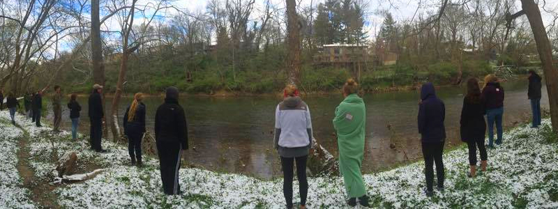 Students standing contemplatively on a riverbank