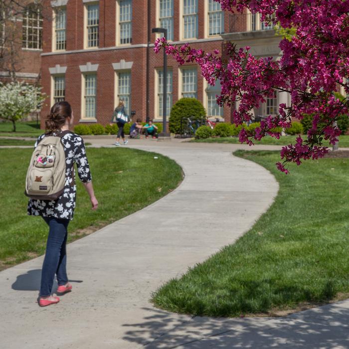 Student walking in front of Irvin Hall in spring  