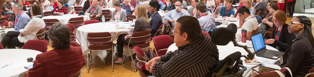 Attendees listen to keynote speaker at a past symposium
