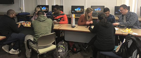 Group of students seated at desks, completing an Agile activity using Lego blocks.