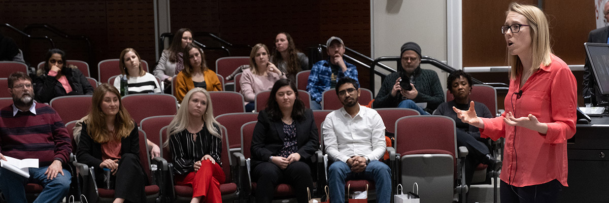 Graduate student delivers presentation before audience in an auditorium.