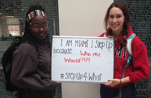 Two female students hold up a white board that says: I am Miami, I step up because who else would. #stepUp4What