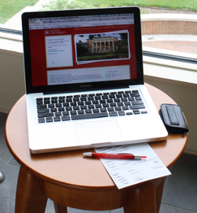 Computer on a desk with paper and a pen