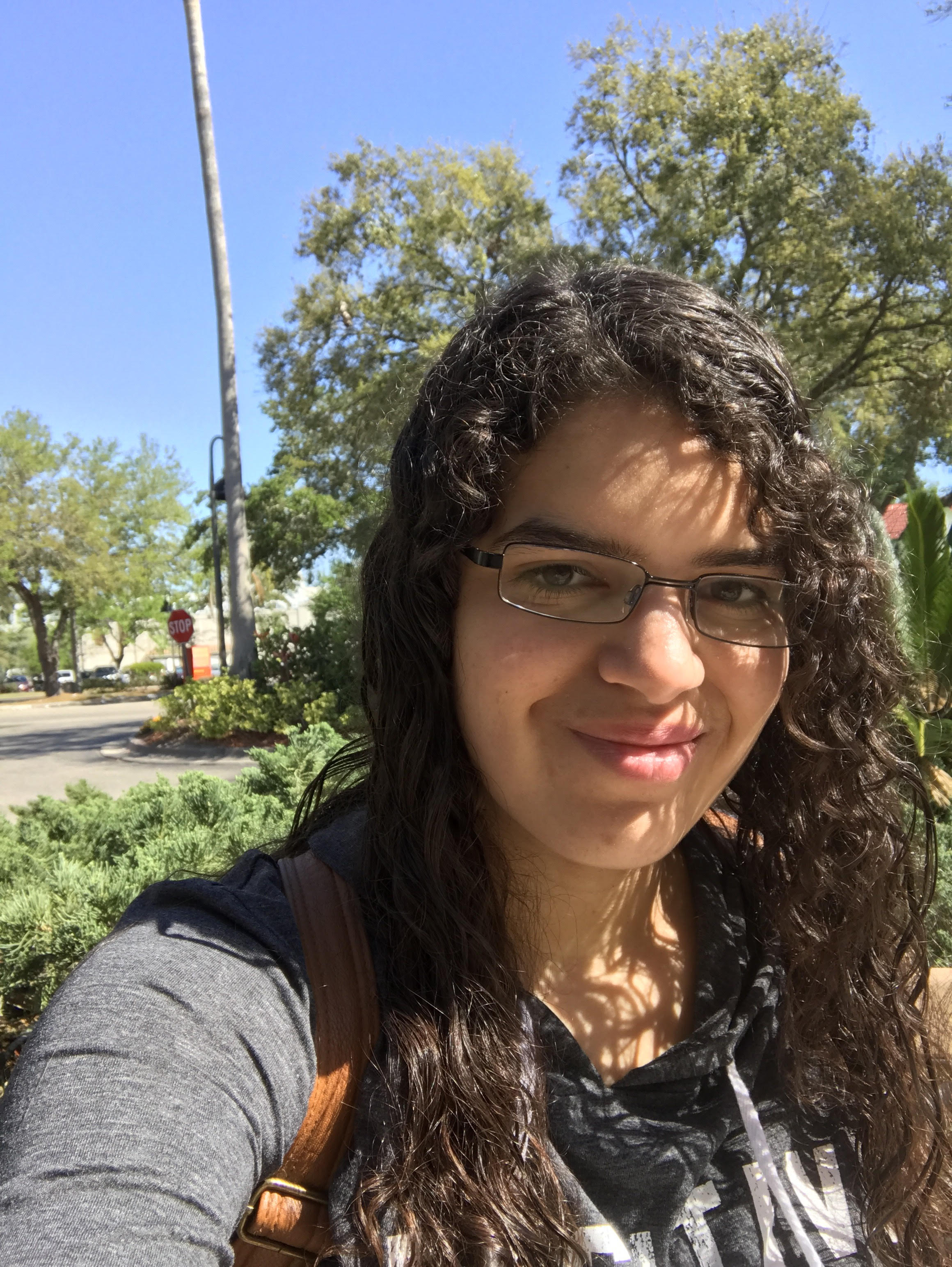 Sofia Olaya wearing a grey sweatshirt standing outside with tress in the background