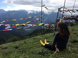 Young woman sitting on a hill overlooking mountains