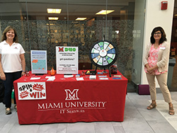 two woman standing at either side of a table advertising security awarneness