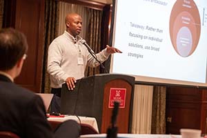 Korey Singleton standing at a podium giving a speech about accessible and inclusive technology