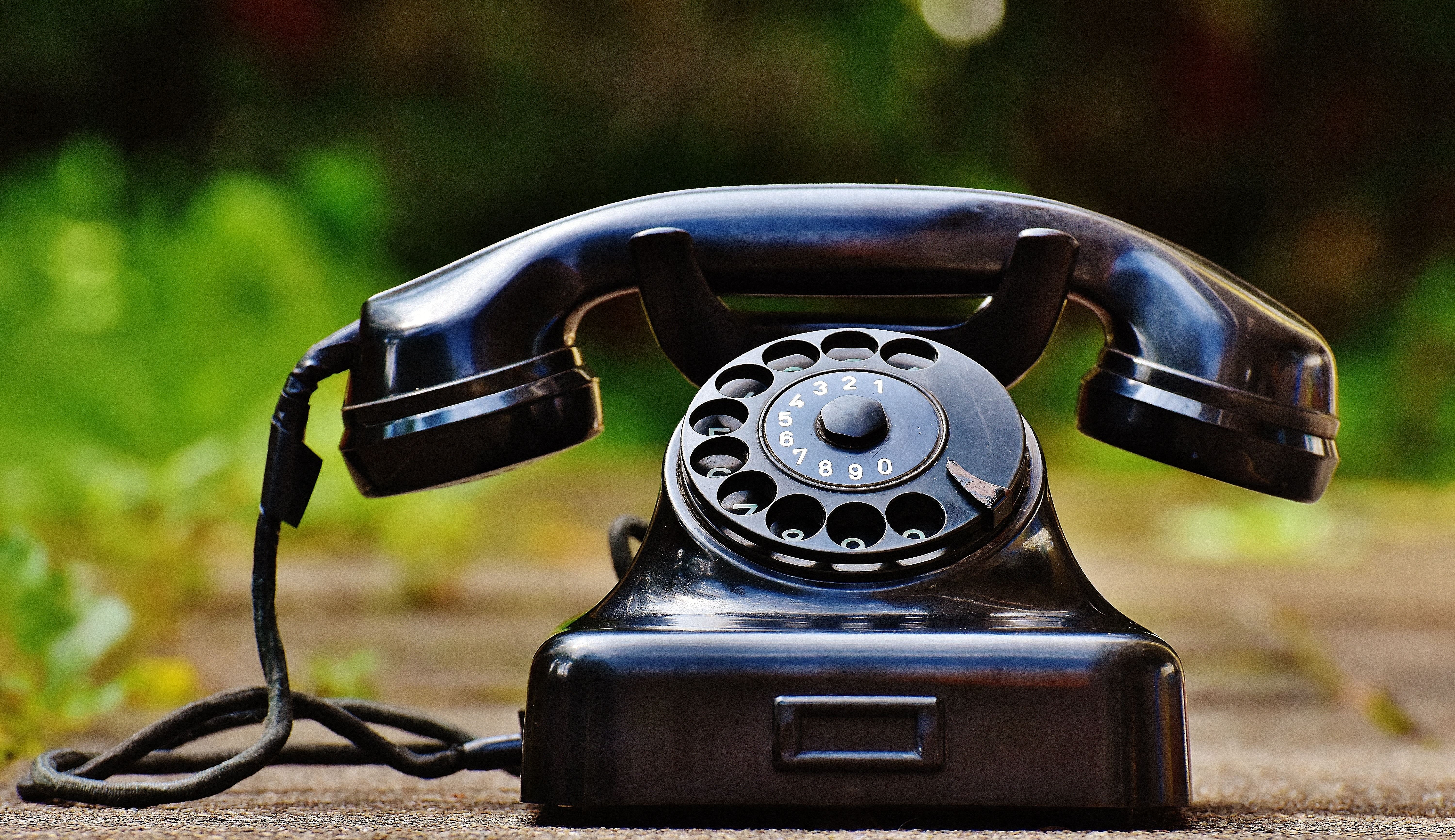 A black antique phone sitting on the ground