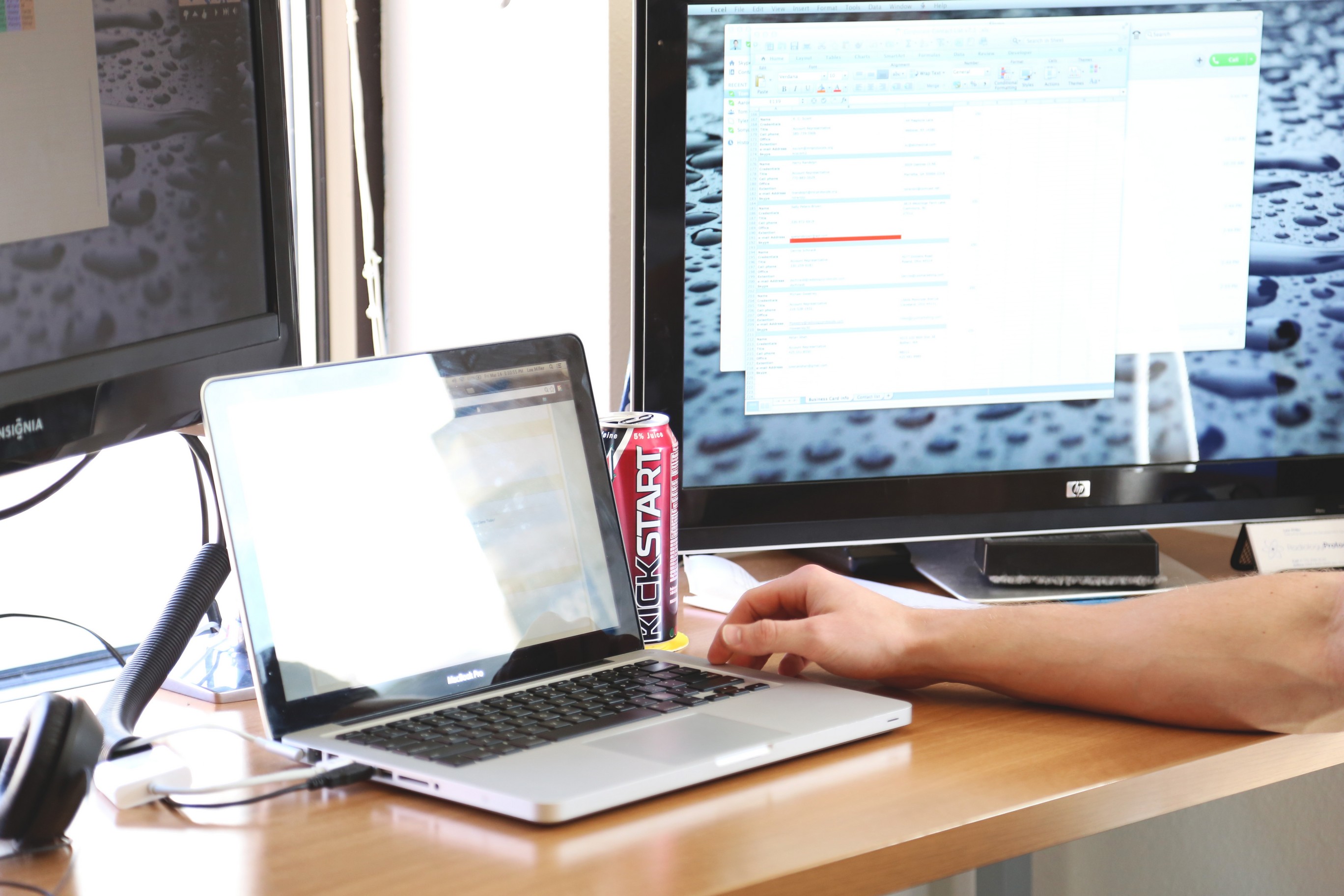 Computer on a desk with a person sitting at it working