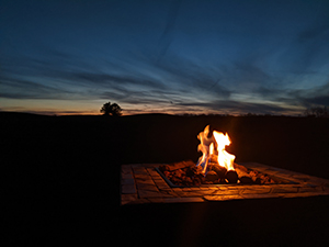 A fire overlooking a golf course at sunset