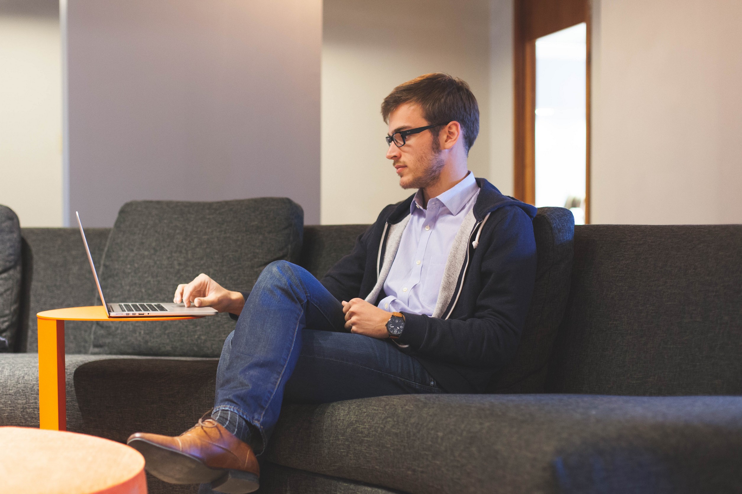 Man sitting on a couch working on his laptop