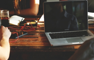 Computer sitting on a desk with someone getting ready to use it in the foreground