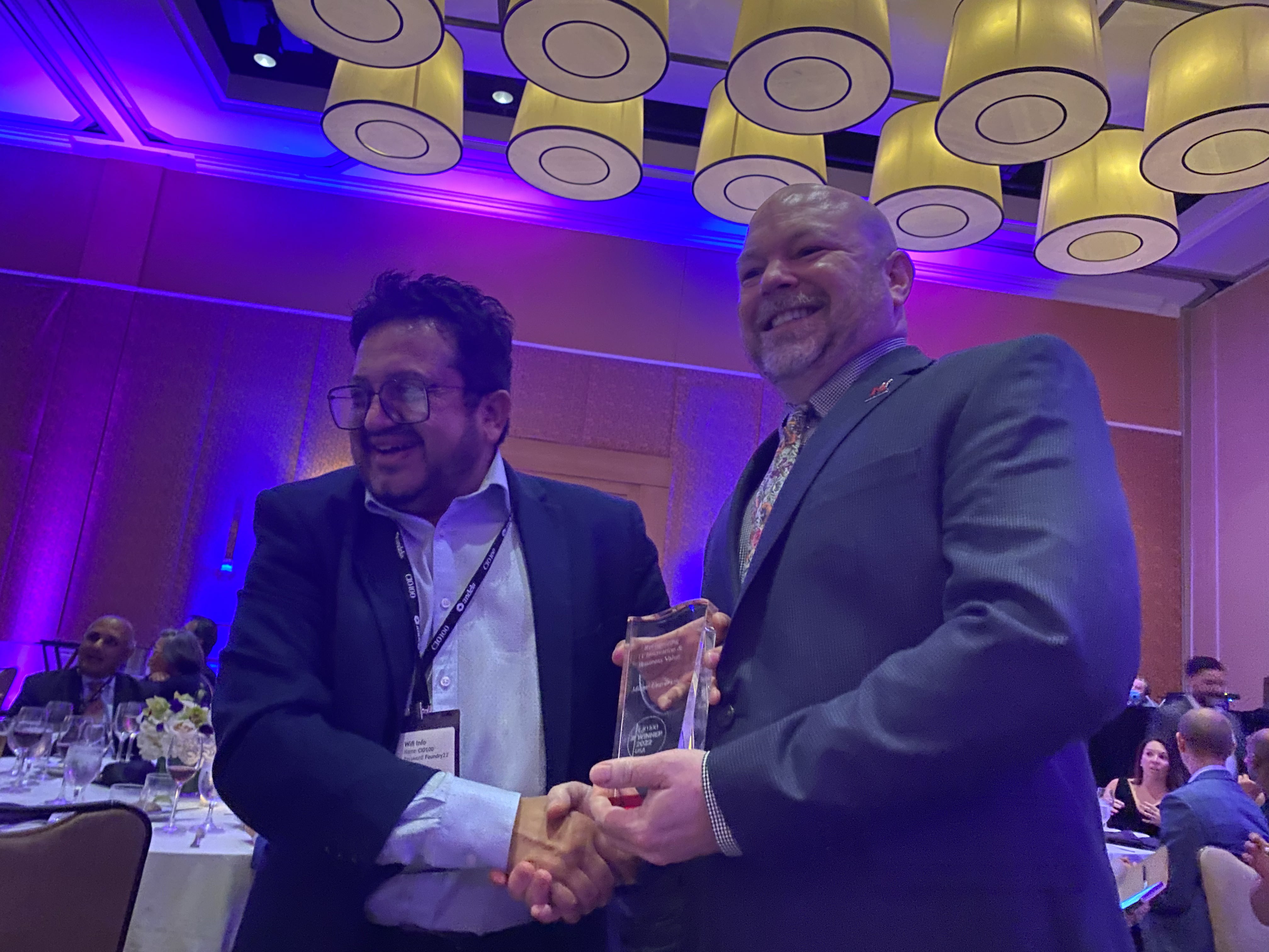 Brian Henebry shakes a man's hand while holding the CIO 100 award