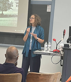 Ann Elizabeth Armstrong stands in front of a classroom holding a microphone