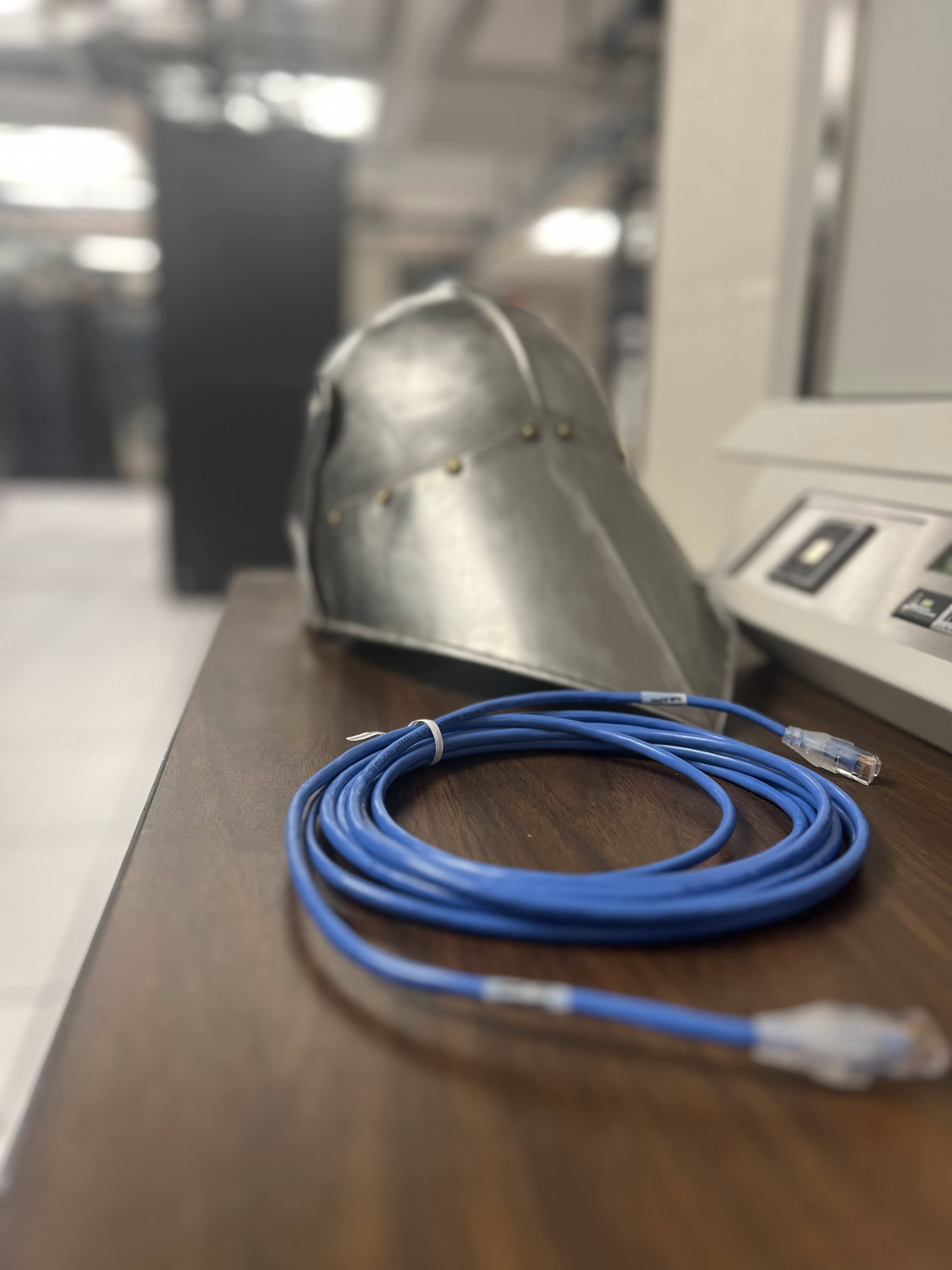 A silver medieval helmet next to a data cable