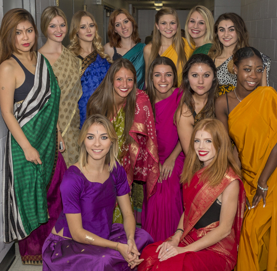 A group of females dressed up in colorful clothes posing for a picture