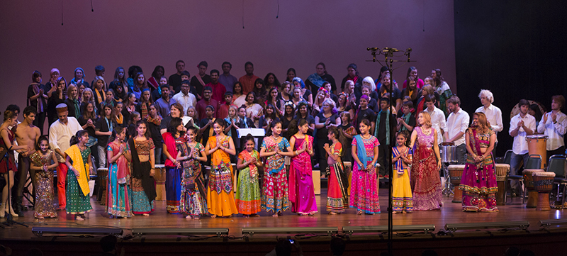 The entire group of dancers and musicians stand on stage at the end of the performance