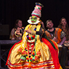 A girl in colorful clothes with her face painted green dances on stage