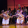 A group of females are dancing on stage while wearing colorful clothes