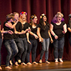 A group of girls stand on stage singing