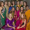 A group of females dressed up in colorful clothes posing for a picture