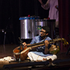 A man sits on stage and plays a sitar